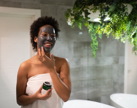 Cheerful African American woman applying mask