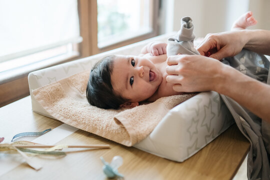Happy baby getting dressed on changing table at home