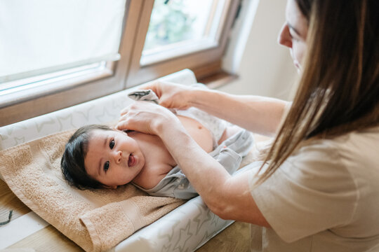 Parent dressing newborn baby at home changing table