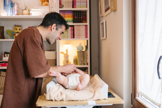 Parent changing diaper on baby at home