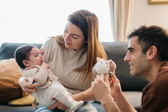 Parents playing with baby at home bringing up infant