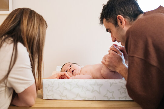 Parents changing baby diaper at home together