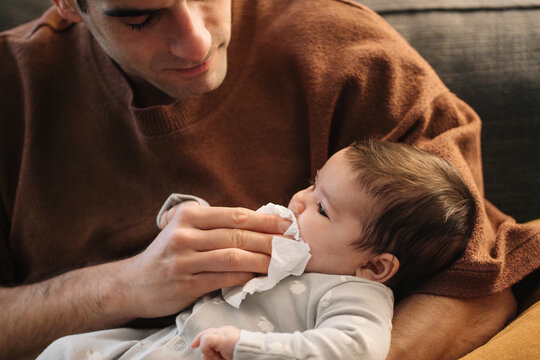 Parent wiping baby's mouth cleaning at home