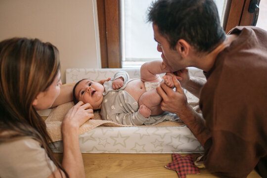 Parents changing baby diaper on changing table