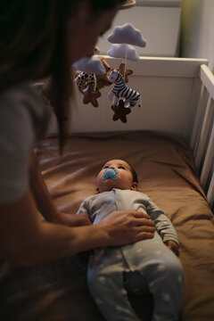 Baby lying in crib looking at hanging animal mobile