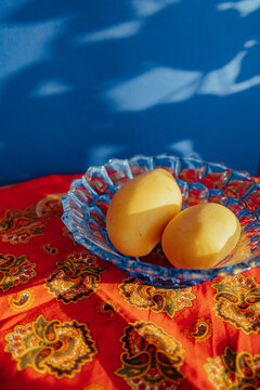 Two mangoes in a bowl on a red tablecloth with patterns