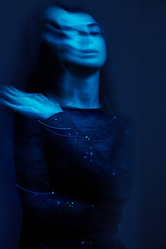 Model poses in blue light with movement captured at a studio