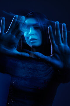 Woman using hands to create an effect in blue light