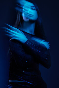 Woman poses with arms crossed in blue light at studio