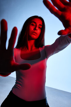 Model poses with raised hands in studio with bright lights