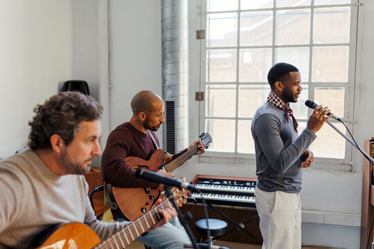Music group playing instruments and singing during rehearsal