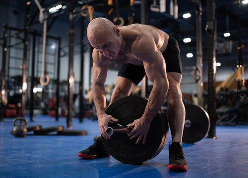 Bald male senior athlete preparing for weightlifting training