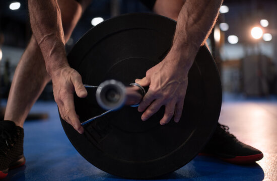 Cropped male senior athlete putting spring collar on barbell