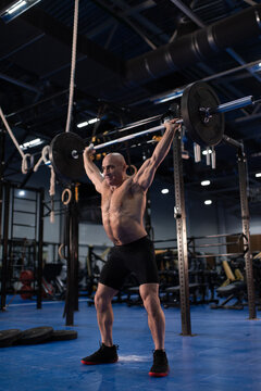 Senior man athlete doing snatch exercise in gym