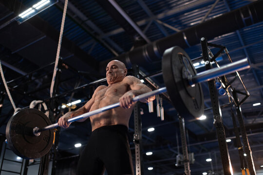 Strained senior athlete lifting barbell