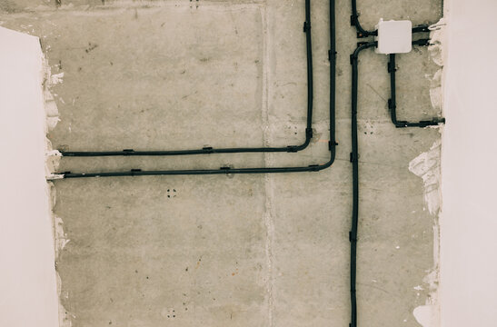 Pipes and Electrical Lines on a Concrete Wall in a Building