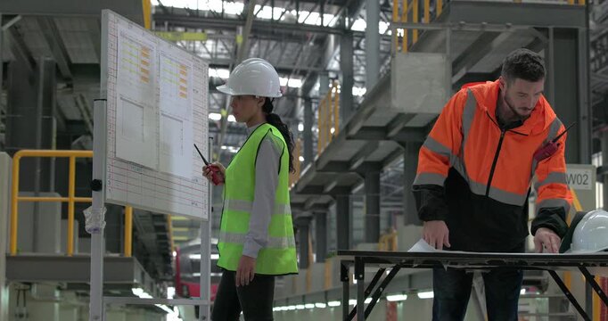 Rail engineers engaged in a planning and review session, focusing on a board displaying schedules, maintenance plans, and performance data of the rail systems. Ensuring efficient rail operations.