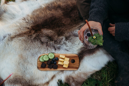 Person enjoying a nordic outdoors picnic on reindeer skin