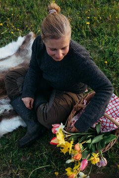 Woman having a picknick on a meadow with spring flowers in a basket