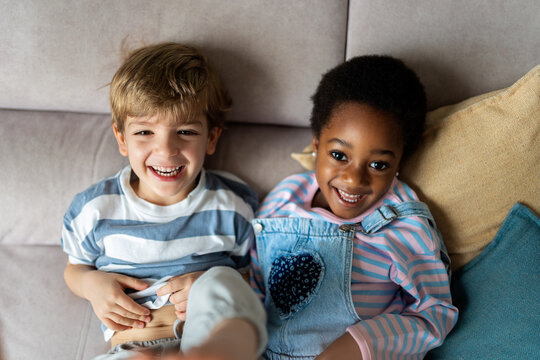 Diverse young friends laughing together on sofa
