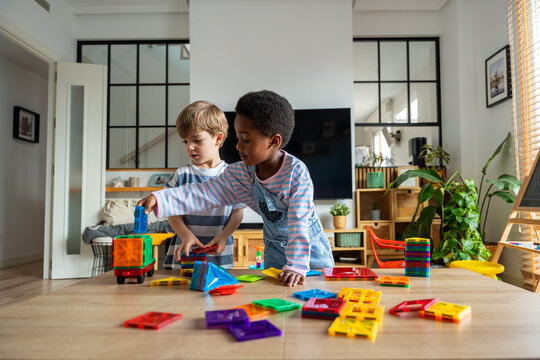Diverse young children playing with magnetic building tiles