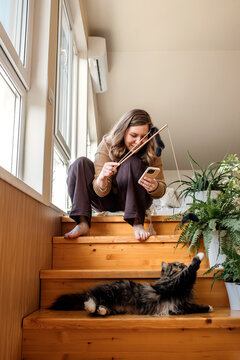 A woman playing with her domestic cat at home.