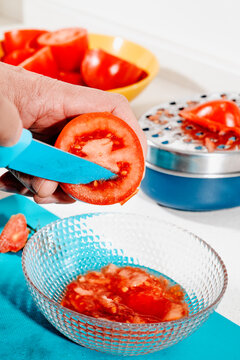 a man scraping seeds from a halved tomato