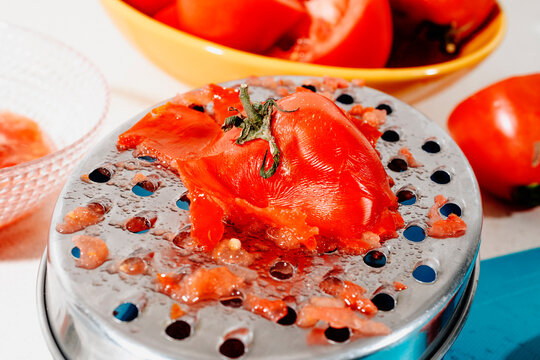 a tomato half resting on a metal grater