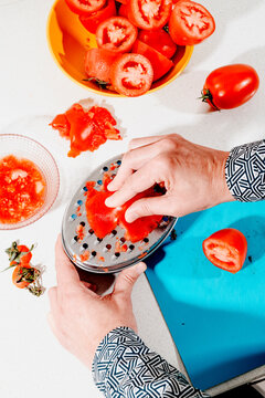 close-up of a man grating tomato flesh