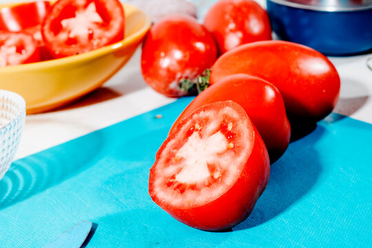 a halved tomato on a cutting board with whole tomatoes