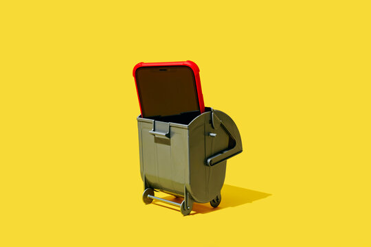 a smartphone inside a small trash bin on yellow