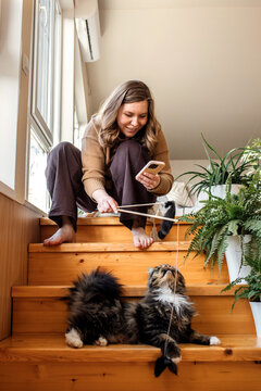 A woman playing with her domestic cat at home.