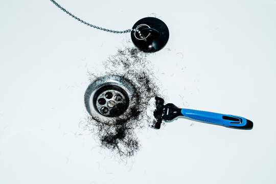 hair gathered near a drain beside a shaving razor