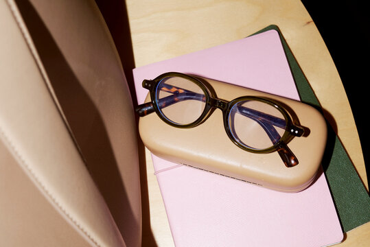 Glasses on a case with notebooks lying on a table