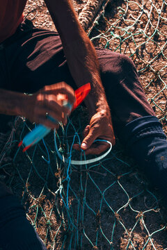 Fisherman mending nets by hand