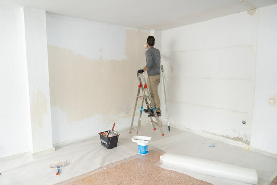 Man painting home interior wall undertaking renovation work