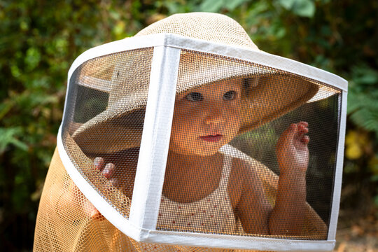 little girl wearing a bee-keeping hat in the forest
