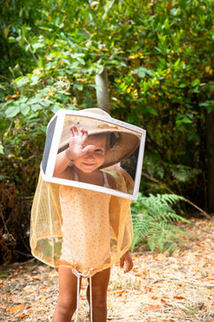 little girl wearing a bee-keeping hat and veil in the forest