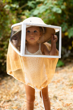 little girl wearing a bee-keeping hat in the forest