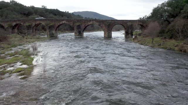 Aerial view of Puente de Piedra in Coria, C&aacute;ceres, Spain. Historic multi-arch stone bridge over Alag&oacute;n River surrounded by rural landscape and flowing water. 