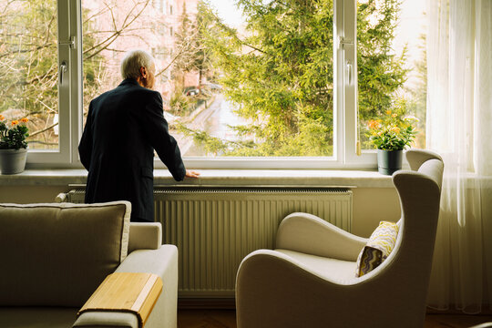 Senior man looking outside window