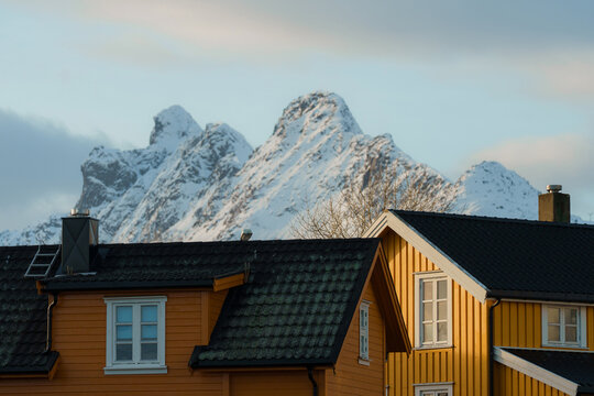 Yellow houses and giant peaks on Lofoten, Norway in winter 