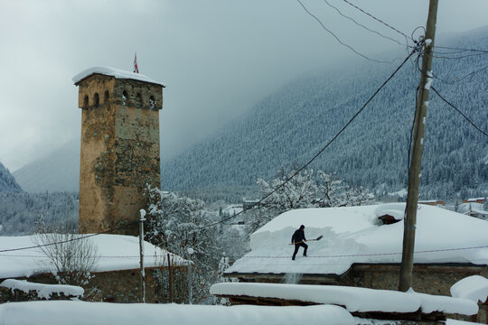 Unrecognisable man shovelling out the snow from the roof 