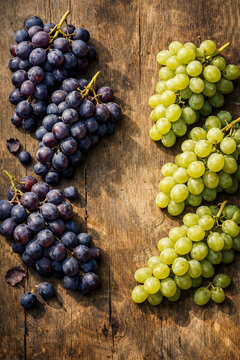 Uvas verdes e roxas sobre mesa r&uacute;stica de madeira