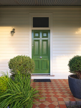 Green Door on House With Plants and Tiles at Entrance