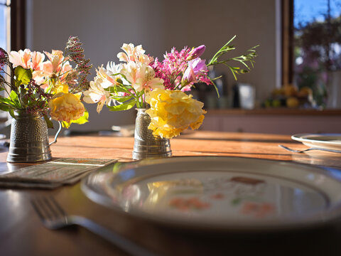 Two Small Vases Hold Fresh Flowers on a Dining Table