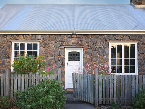 Stone Cottage With White Door and Wooden Fence in a Rural Area