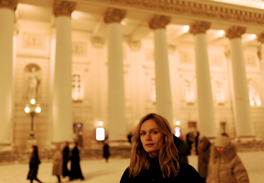Woman Stands by Columns in a City at Night During Winter Season