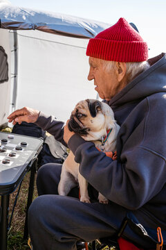 A man with a dog at a tent with checkers.
