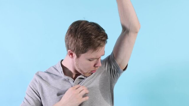 Man with sweaty armpits on light blue background